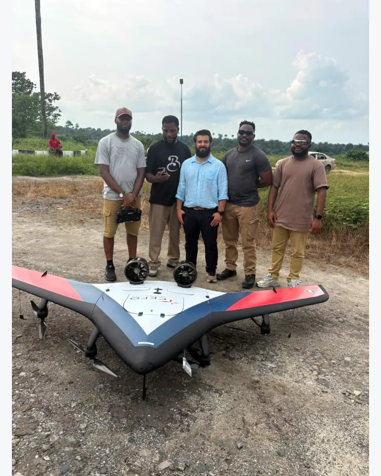 Five people standing behind the red, blue and white CEFO aircraft at an outdoor field location